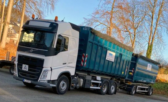 Moderner Lkw mit Anhänger für Containertransport auf einem Firmenhof im Freien.
